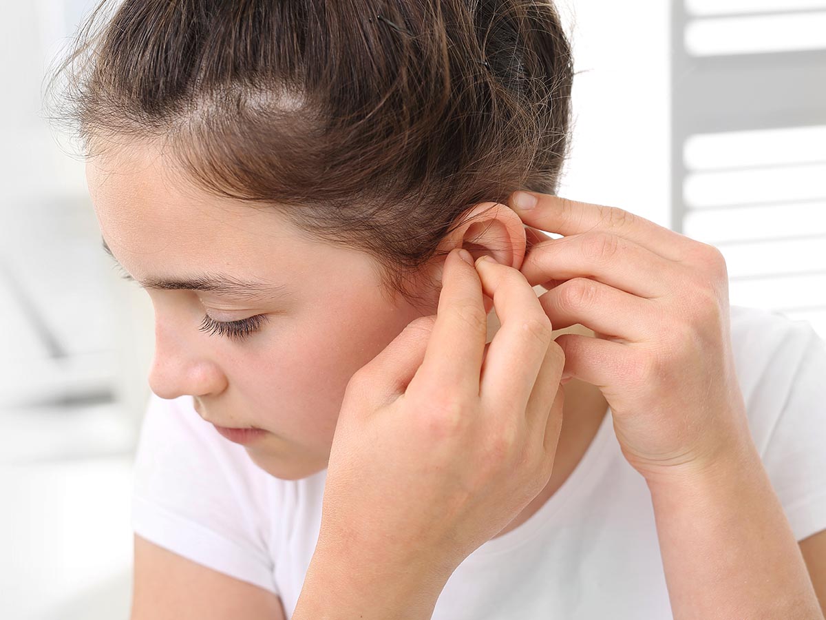 Girl putting hearing aid in her ear