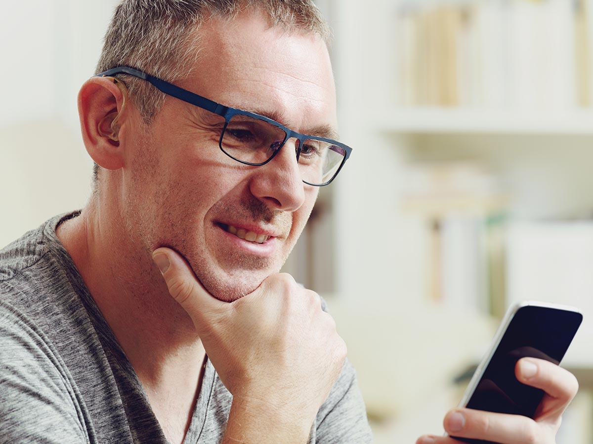 Man wearing hearing aid using a mobile phone